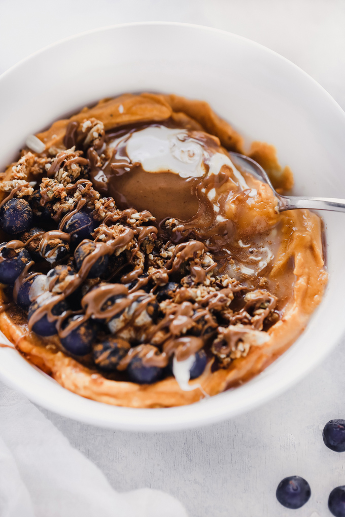 Vegan Sweet Potato Breakfast Bowl - Topped with blueberries, almond butter, and dairy free yogurt, this is packed with fiber, healthy fats and so easy to make! You can meal prep this and have it ready to go with all the right ingredients to fuel your day! NeuroticMommy.com #vegan #breakfast #sweetpotatoes